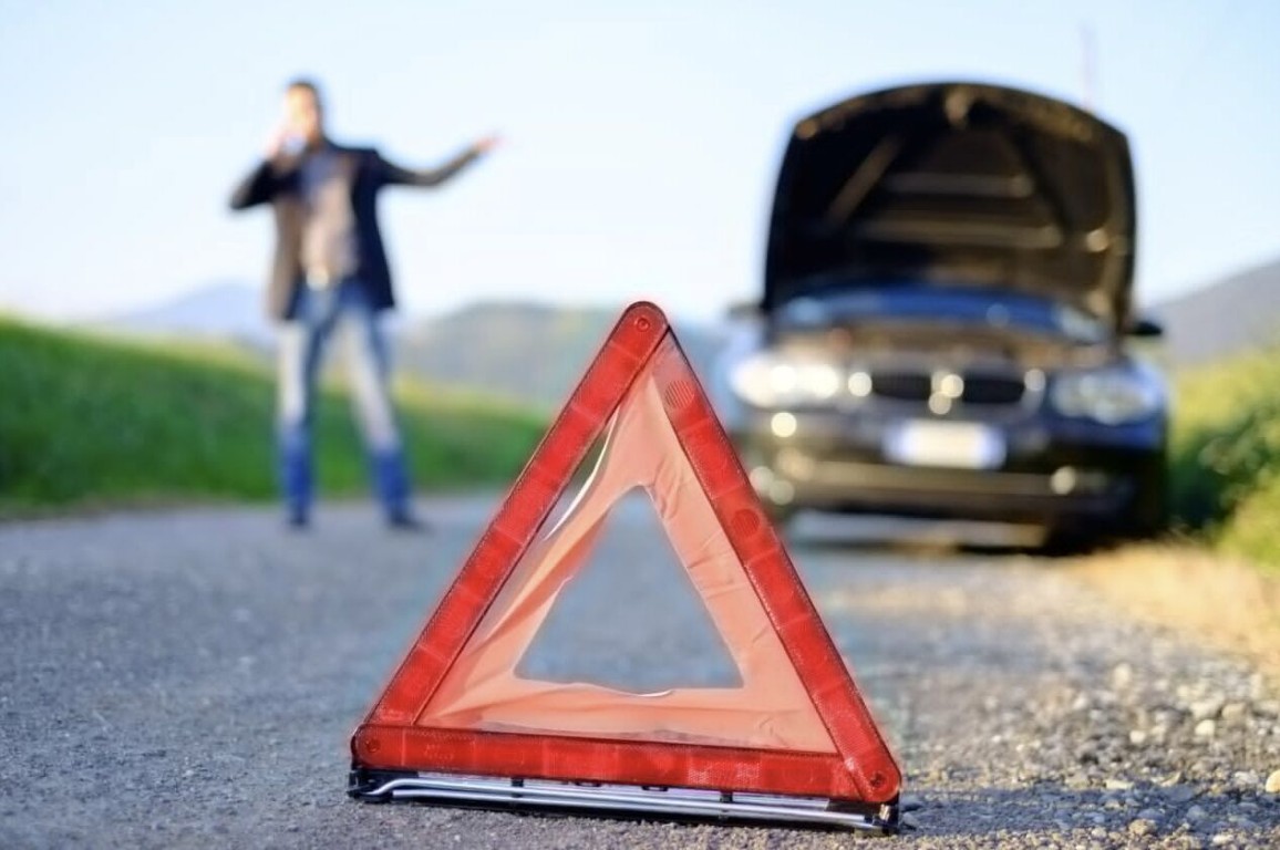 Roadside assistance for stranded motorist with broken down car and warning triangle